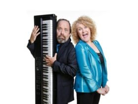 Man with keyboard and woman in blue jacket posing for photo