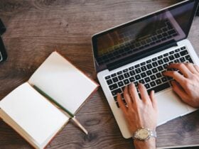Image of someone typing on a laptop with notebook next to them