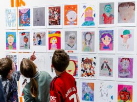 Young people looking at colourful artworks hanging on a gallery wall