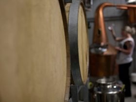Rum barrels in the foreground with Ally distilling in the background.