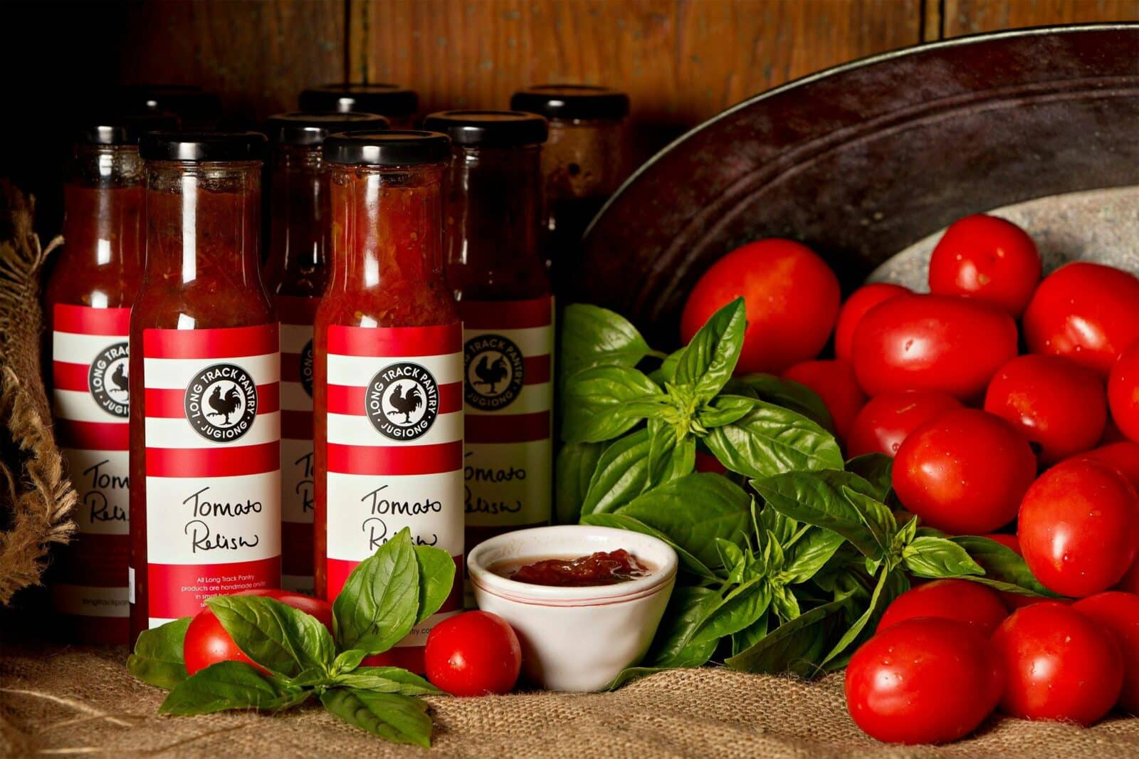 Jars of homemade relishes with fresh tomatoes and basil