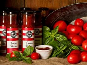 Jars of homemade relishes with fresh tomatoes and basil