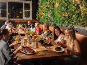 group of people sitting at a table eating drinking and smiling in Outback Steakhouse