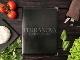 Menu surrounded by cheese, tomatoes, herbs and cutlery