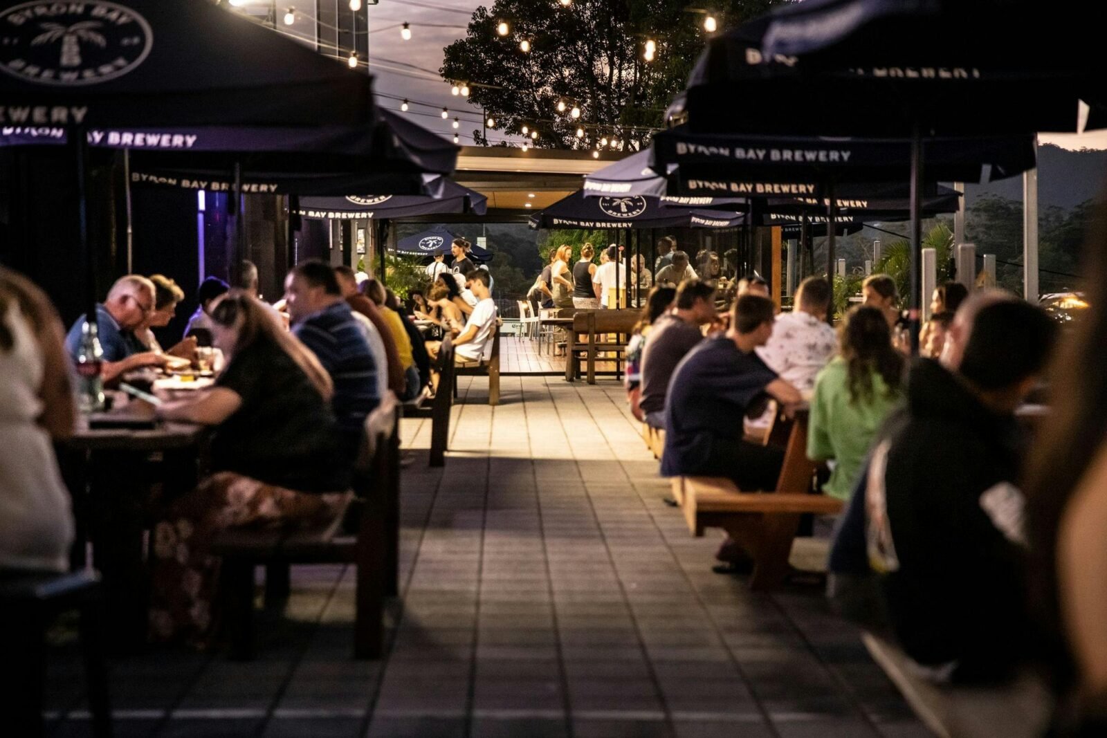 Looking through people sitting at outdoor tables, into the restaurant and to the kids area at sunset