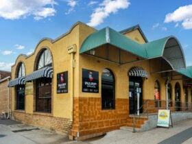 Exterior of Warp Arcade building with yellow walls, arched windows and the Warp Arcade signage