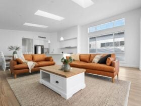 Large open living area with 2 brown leather lounges, large white modern kitchen, 3 skylights