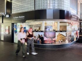 Two women walking past an information hub for Sydney