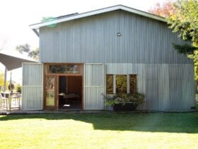 A corrugated iron shed with timber finishings with a rustic bathtub filled with florals