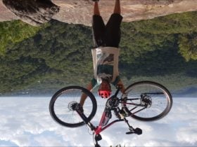 e-bike tour rider with bike held high over breathtaking view