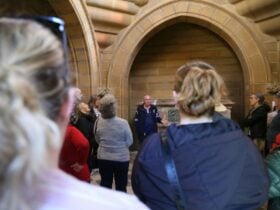 Tour group listening to a guide inside a historic sandstone Frazer mausoleum at Rookwood Cemetery