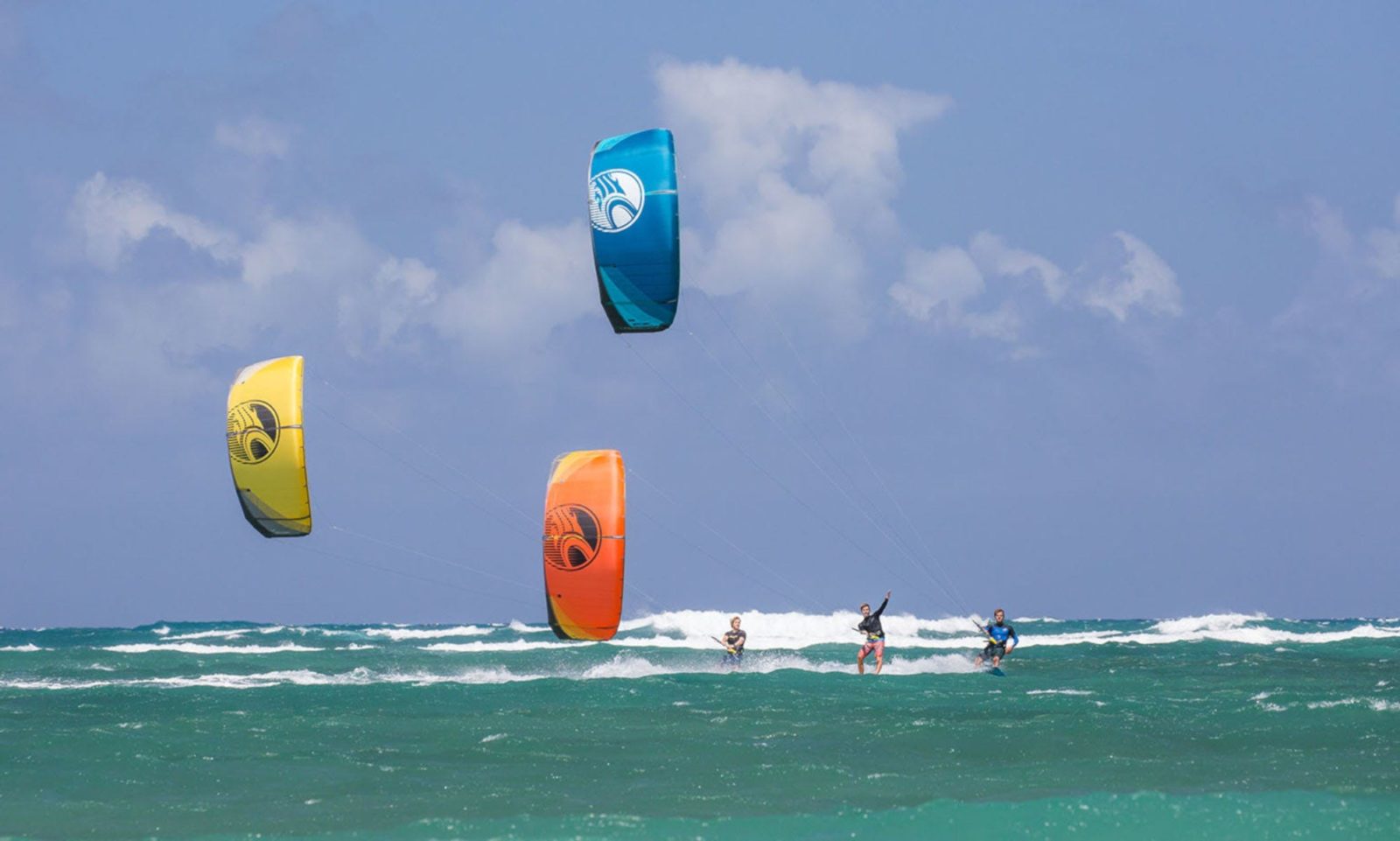 3 kitesurfers all surfing in towards the beach