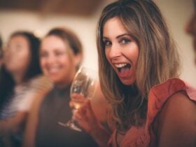 A lady holding a wine glass smiling at the camera