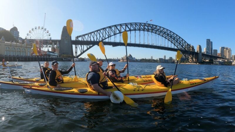 Team kayaking photo under the Sydney Harbour Bridge