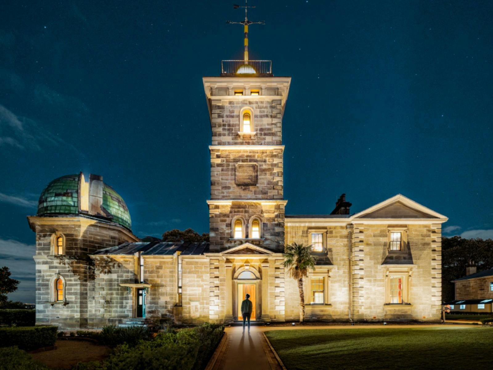 Person walking into illuminated sandstone observatory