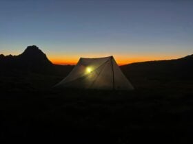 A tent in the mountains as the sun sets.