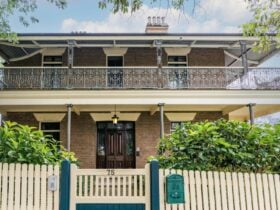 front facade of historic home with balcony and picket fence