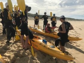 A group of people standing on the beach getting ready to kayak to Broughton Island