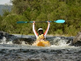 A kayaker is paddling over a nymboida river kayaking rapid.