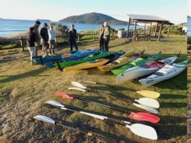 A group pf people standing around a group of Kayaks preparing to Kayak to Broughton Island