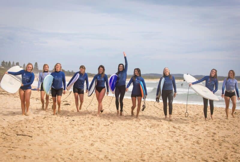 women walking with surfboards at the beach