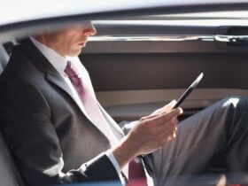 A business man sitting in the back of a car doing their work
