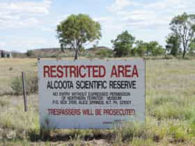 Sign at entry gate into the Alcoota Fossil Beds researchers field camp site, which can be seen in the background.