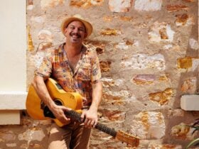 Photograph of musician David Spry holding a guitar and smiling