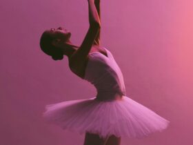 Artist of The Australian Ballet wearing a white tutu performs an elegant backâarched pose with arms