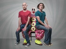 Umbilical Brothers sitting on the lap of a clown called Roadie, looking uncomfortable