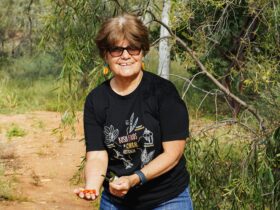 Rayleen Brown from Kungkas Can Cook stands in front of a tree and shows some natives seeds