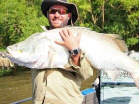 Man in a fishing boat holding a fish.