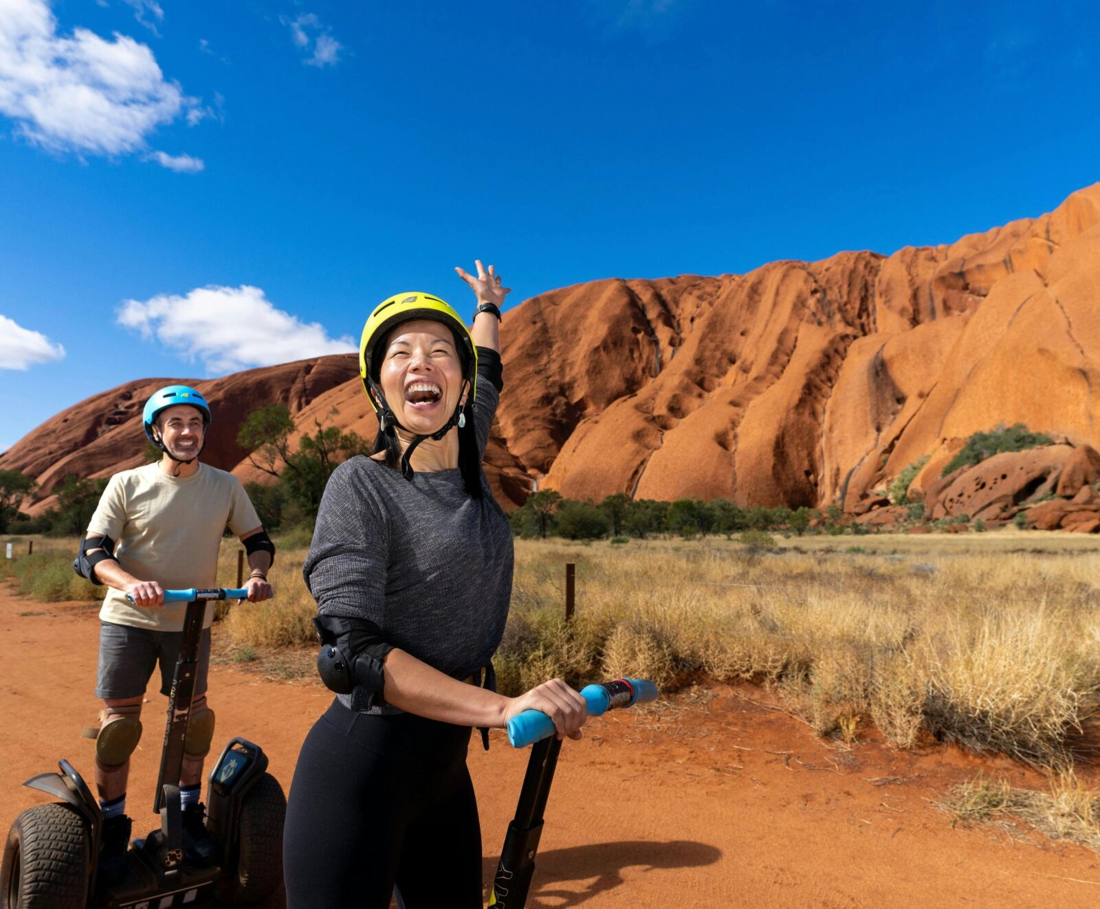 A couple glide past Uluru on Segways, from their expressions it