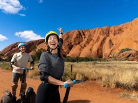 A couple glide past Uluru on Segways, from their expressions it
