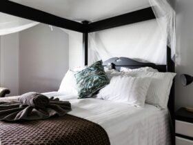 4 poster bed with white linen and maroon and teal bedding