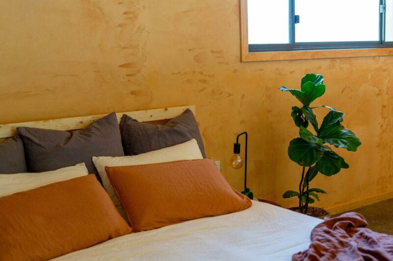 bedroom with natural linen, clay walls and plant at cabin