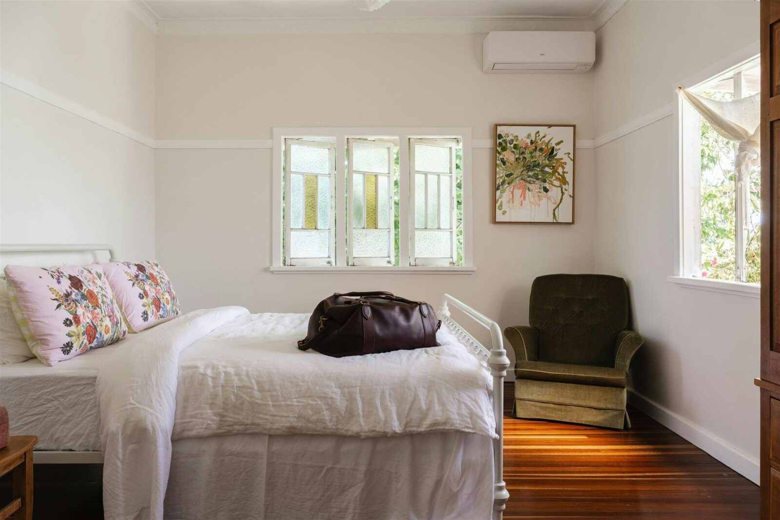 Bedroom with antique chair in the corner and white linen sheets.