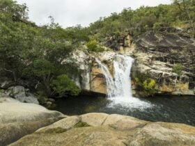 Water cascading over granite boulders into a natural pool.