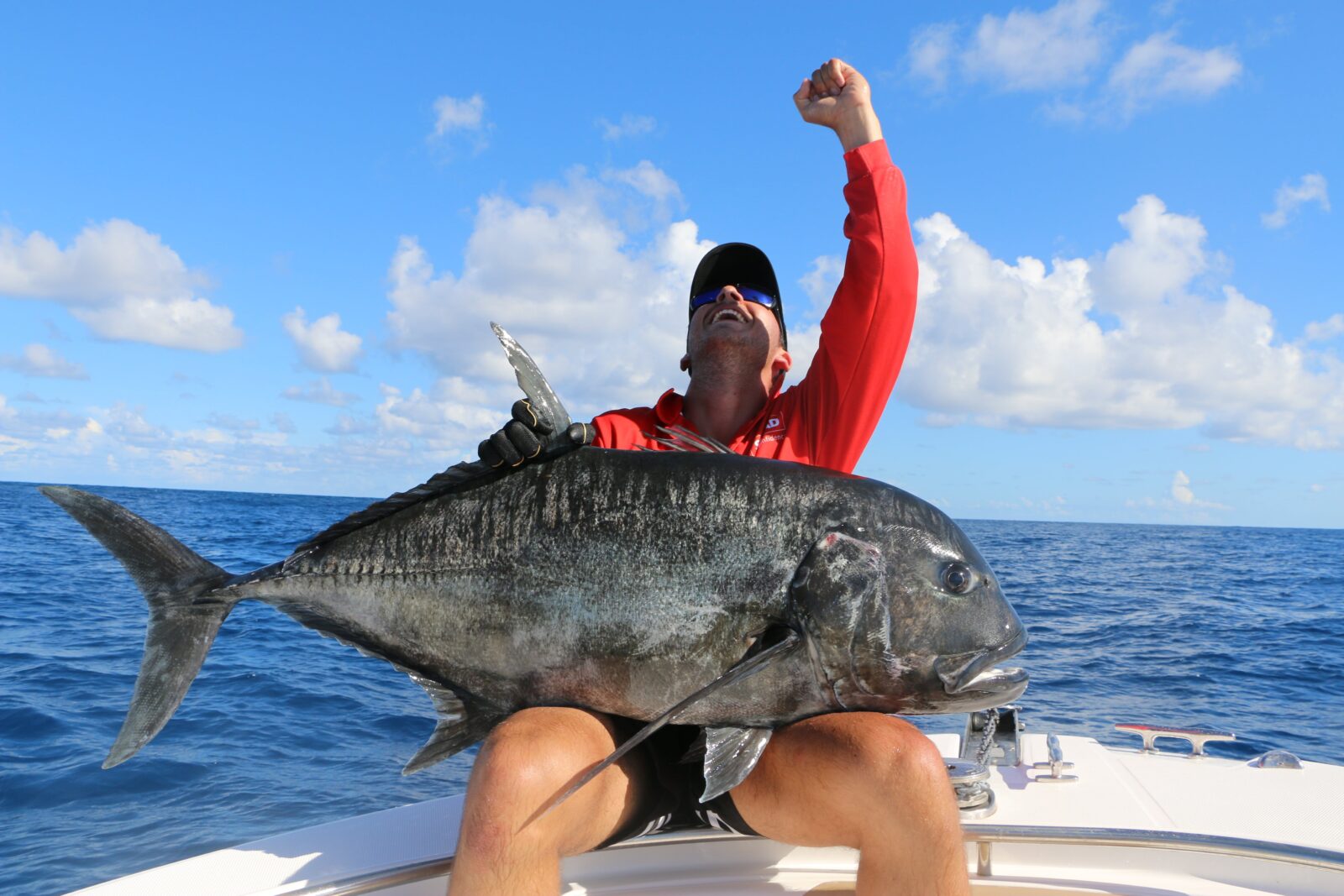 photo showing a man sitting on a small boat with a large GT on his lap