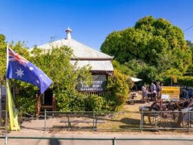 image shows cottage with foliage. to the right are people surrounding a panning gold trough