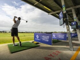 Man Swinging Golf Club on Driving Range