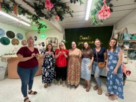 Happy artists paint ther artwork in a paint and sip experience under a beautiful indoor tree studio