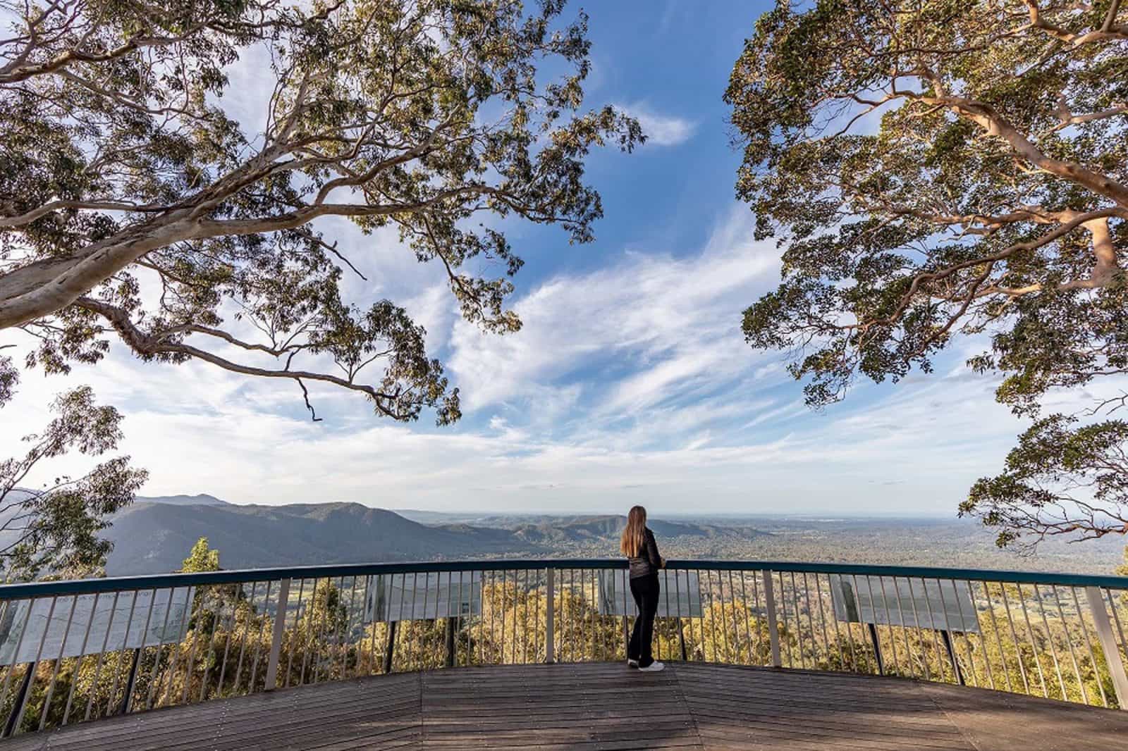 Woman standing on a deck looking at view of mountains and valley