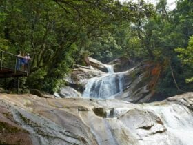 Three people standing at a lookout looking at waterfall.
