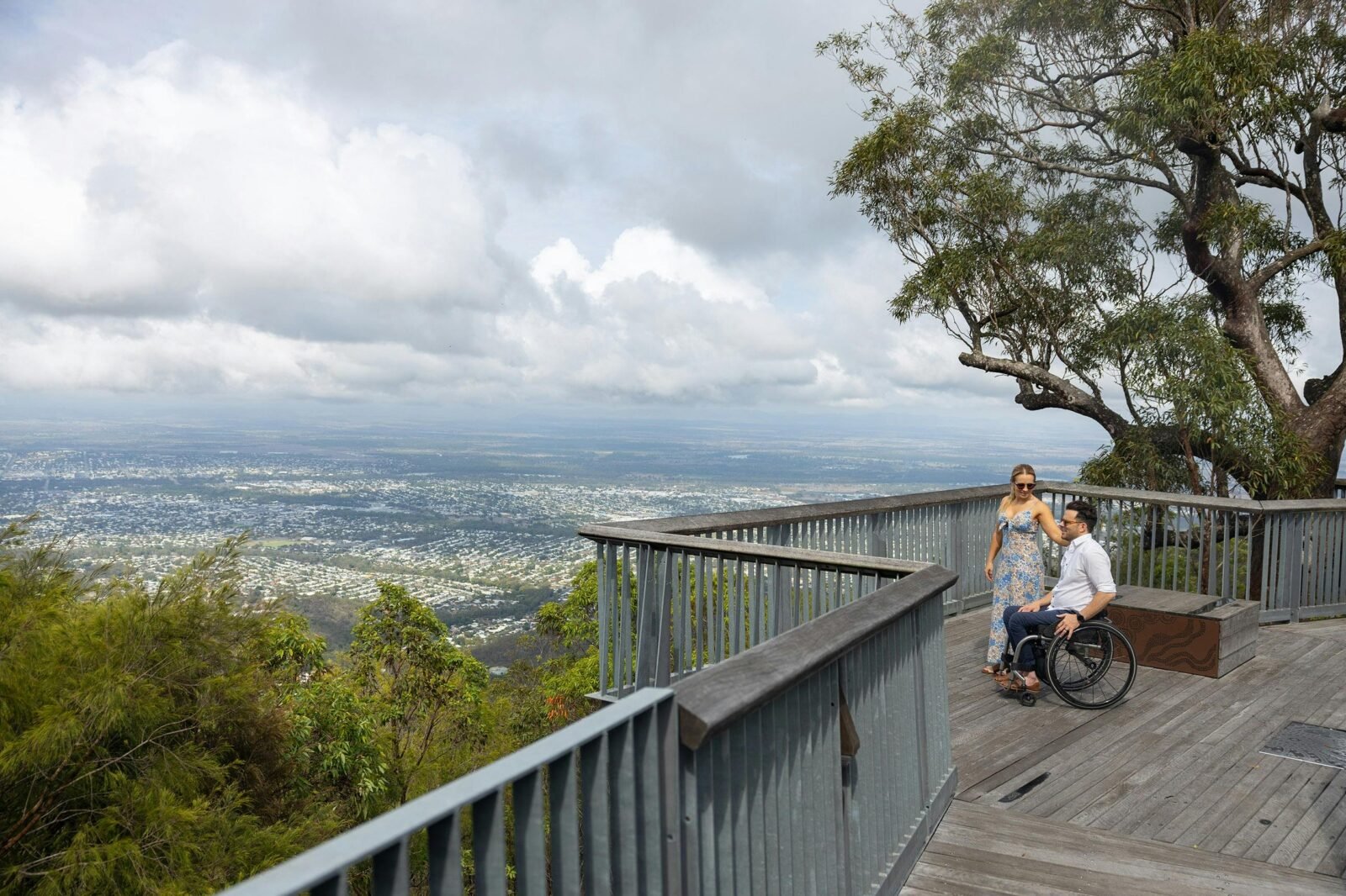 A man, who is in a wheelchair, stands with his wife overlooking a beautiful view of Rockhampton.