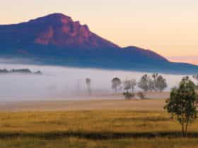 Mount Maroon with base shrouded in fog and farmlands in foreground.