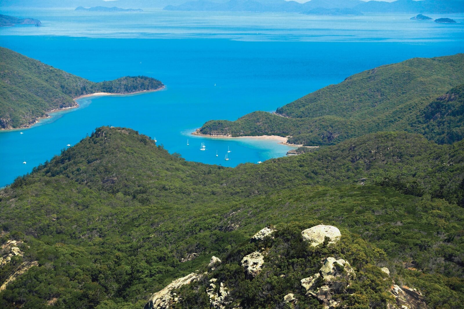 View from the hilltop overlooking the sailing boats in blue ocean and other islands in distance