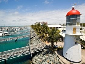 Aerial shot of the Pine Islet lighthouse at the Mackay Marina, boats, jettys, rockwall and water.