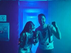 A man and woman in Saboteurs vests celebrate and laugh together in a blue-lit corridor.