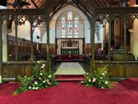 The interior of the church showing the chancel and altar along with stained-glass windows.